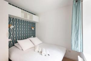 Cama blanca con almohadas blancas y cortinas azules en L'Ecrin Vert - 150m Restaurant 3 étoiles, en Vonnas