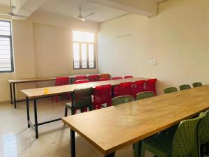 a room with tables and chairs in a classroom at Abuzz Oxfordcaps Cedar Homes in Jhājra