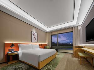 a bedroom with a white bed and a large window at Hilton Garden Inn Guilin Yangshuo in Guilin