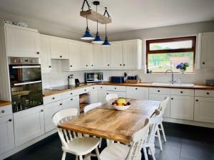 - une cuisine avec une table en bois et des placards blancs dans l'établissement Cosy 3-bedroom home with garden and log burner., à Bradford-on-Avon