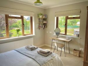 a bedroom with a bed and a desk and windows at Cosy 3-bedroom home with garden and log burner. in Bradford on Avon
