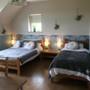 two beds in a room with two tables and two lamps at Wild Atlantic Stay Guest House Self-Catering in Galway