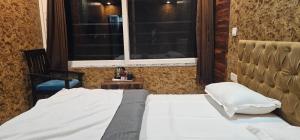 a bedroom with a white bed and a window at Hotel Mussoorie Gold Mary in Mussoorie