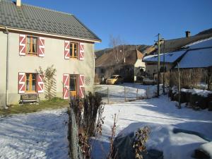 una casa con ventanas rojas y blancas en la nieve en Gîte au chemin des Cordonniers, en Gresse-en-Vercors