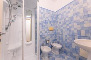 La salle de bains est pourvue de carrelage bleu, de toilettes et d'un lavabo. dans l'établissement Bilocale Corso Italia 697 2° piano con balcone, à Gallipoli