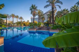 ein Pool mit Palmen und ein Gebäude in der Unterkunft Concorde De Luxe Resort - Prive Ultra All Inclusive in Lara