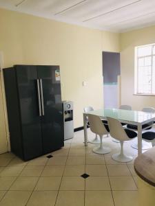kuchnia ze stołem i czarną lodówką w obiekcie Derrick Guest House w mieście Johannesburg