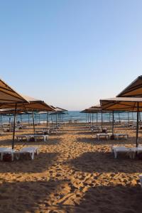 einen Strand mit Tischen und Sonnenschirmen und dem Meer in der Unterkunft Miramare Beach Hotel - Ultra All Inclusive in Side