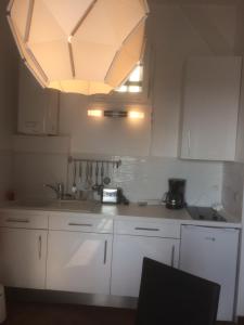 a kitchen with white cabinets and a large chandelier at Au Soleil Couchant in Trouville-sur-Mer +25 photos