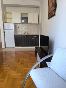 een keuken met een witte koelkast en een houten vloer bij Apartman Quality in Voždivac