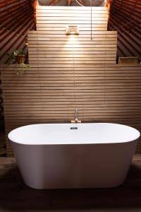 a white bath tub in a bathroom with a wooden wall at Yeruu lodge in Jargalant