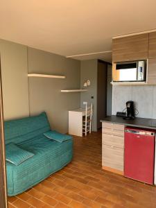 een slaapkamer met een groen bed en een keuken bij Appartement Domaine de la Coudouliere + piscine (mai à octobre) in Six-Fours-les-Plages