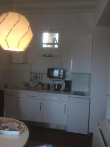 トゥルヴィル・シュル・メールにあるAu Soleil Couchantの白いキャビネットと照明付きのキッチン