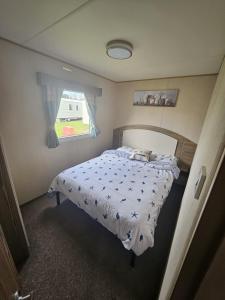 1 dormitorio con 1 cama con edredón blanco y ventana en Lovely 3 Bed Caravan near to beach 5 star Reviews, en Cleethorpes