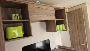 a kitchen with wooden cabinets and a tv in a room at Lovely 3 Bed Caravan near to beach 5 star Reviews in Cleethorpes