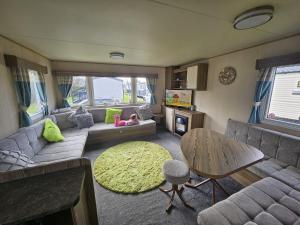 sala de estar con sofá y mesa en Lovely 3 Bed Caravan near to beach 5 star Reviews, en Cleethorpes
