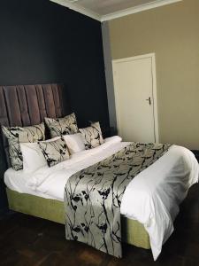 sypialnia z dużym łóżkiem z białą pościelą i poduszkami w obiekcie Derrick Guest House w mieście Johannesburg