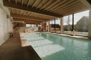 a swimming pool in a house with windows at Les Arbres sous le vent à 10 min de Pairi Daiza in Jurbise