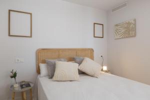 un letto bianco con cuscini bianchi sopra di Apartamento con vistas en Puerto Banús a Marbella