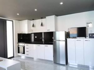 a kitchen with white cabinets and a stainless steel refrigerator at Sunrise Luxury Seaside Apartment in Paránimfoi +5 photos