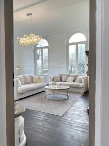 una sala de estar con muebles blancos y una lámpara de araña. en L'Orangerie du Château - Outdoor swimming pool, en Blandainville