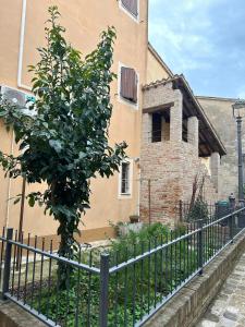 un árbol junto a una valla delante de un edificio en Al Castello en Tavullia