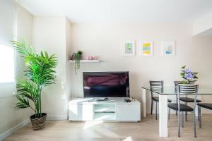 a white living room with a table and a tv at CARTAGENAFLATS, Apartamentos Anfiteatro Romano in Cartagena