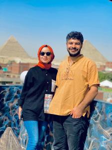 a man and a woman standing in front of pyramids at Horus Pyramids Inn in Cairo