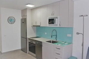 a kitchen with white cabinets and a sink at Can Jané Port d Alcudia in Port d'Alcudia