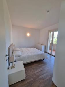 a white bedroom with a bed and a window at Residence San Francesco in Tirrenia