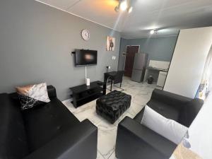 a living room with two black couches and a tv at Beyond Comfort Apartment in Pretoria