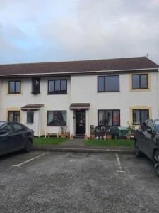 una casa blanca con coches aparcados en un estacionamiento en 2 Bedroom apartment in Brean, en Brean