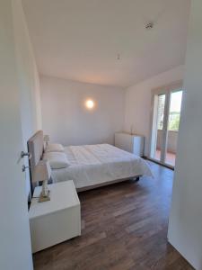 a white bedroom with a bed and a wooden floor at Residence San Francesco in Tirrenia