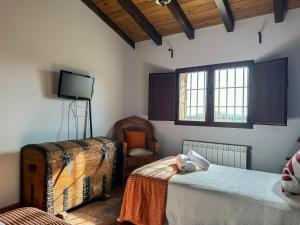 a bedroom with two beds and a tv and a chair at VILLA AMANECER in Candeleda