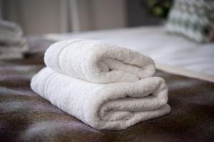 una pila de toallas blancas sentadas encima de una cama en The Kings Arms Otterton en Budleigh Salterton