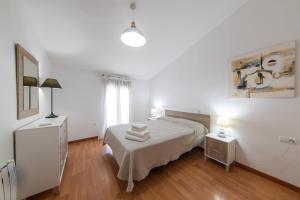 a white bedroom with a bed and two night stands at Apartamentos Moon Dreams Puerto in El Puerto de Santa María