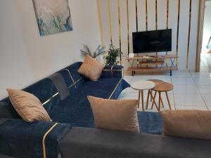 a living room with a blue couch and a television at Sapphire apartment in Agios Nikolaos