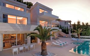 una casa con una palmera frente a una piscina en Villa Brac Neptuno - 6 Bedroom Luxury Villa - Sauna - Gym - Sea Views, en Selca