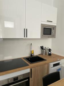 a kitchen with white cabinets and a sink and a microwave at Exyca Metropolitano in Madrid