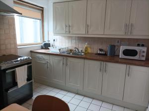 a kitchen with white cabinets and a microwave at Tom Dick and Harriet's Accommodation in Dublin