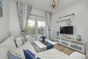 a living room with a white couch and a tv at Stylish Apartment Grunwaldzka by Rent like home in Świnoujście
