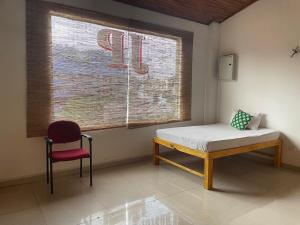 a room with a bed and a chair and a window at JP Hostels & Apartment in Kandy