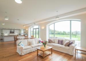 a living room with two white couches and a kitchen at Swydd Long Barn Swyddffynnon in Ystrad-Meurig