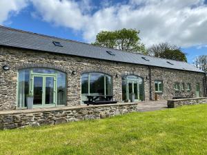 a stone house with large windows and a lawn at Swydd Long Barn Swyddffynnon in Ystrad-Meurig