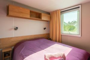 a bedroom with a purple bed and a window at Camping Les Charmettes in Les Mathes +13 photos
