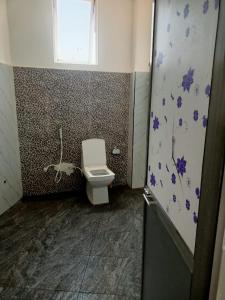 a bathroom with a toilet with purple flowers on the wall at JP Hostels & Apartment in Kandy
