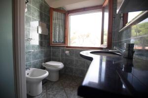 łazienka z toaletą, umywalką i oknem w obiekcie La Torretta - HelloElba w mieście Marina di Campo
