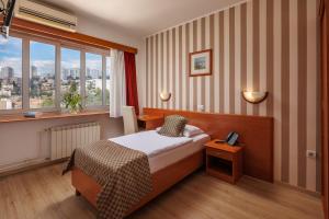a hotel room with a bed and a window at Hotel Neboder in Rijeka