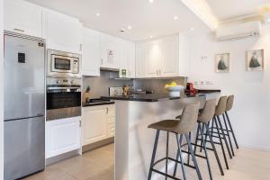 a kitchen with white cabinets and bar stools at Phenthouse Monaco - Jacuzzi - City Center - Sea View in Albufeira
