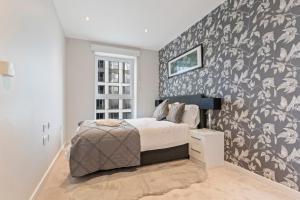 a bedroom with a bed with a black and white wallpaper at Elegant 2 bed flat on 20th floor near many attractions in London
